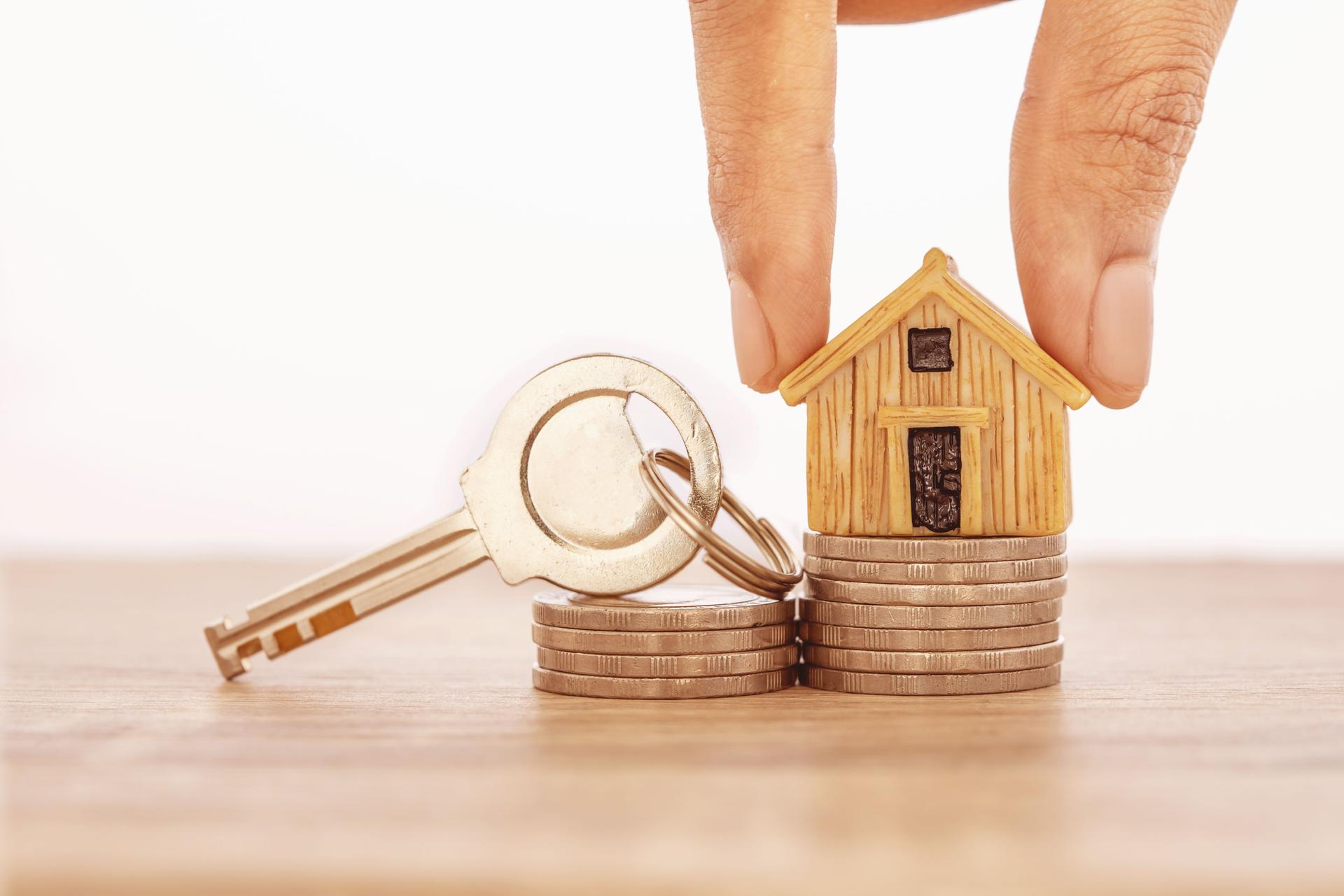 Close up hand putting house model place on stacking of money coin for home mortgage and loan ,  refinance or property investment concept